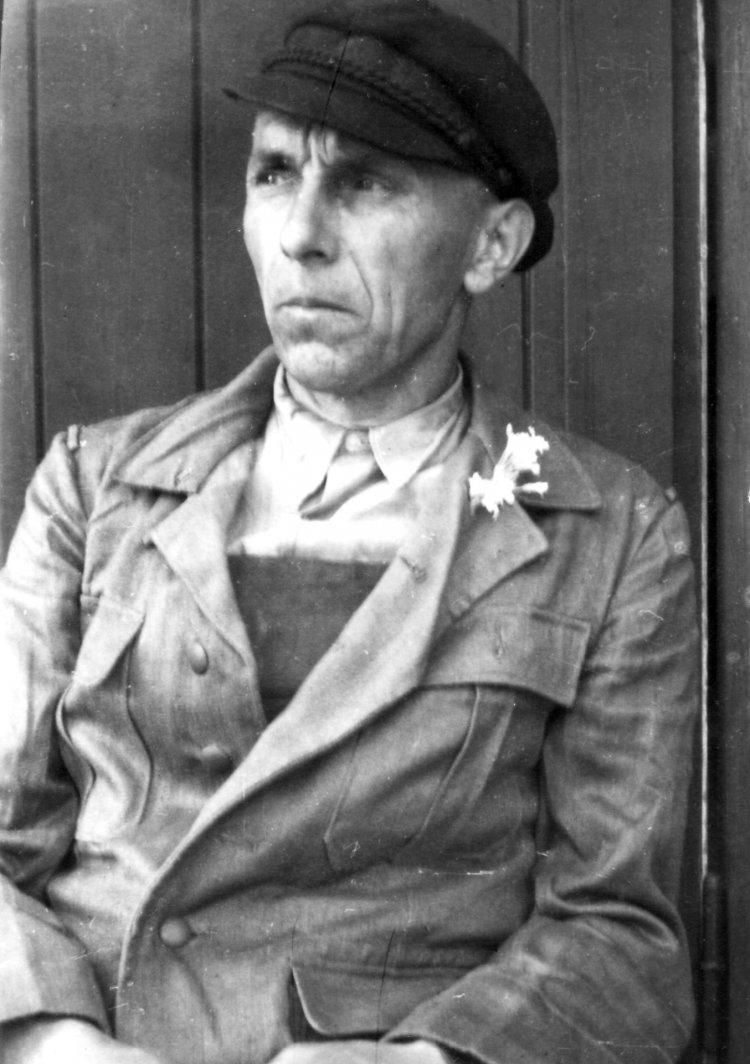 Adolf Dobschat sitting in front of a barrack wall.
Photographer unknown, 1 May 1945
Private collection